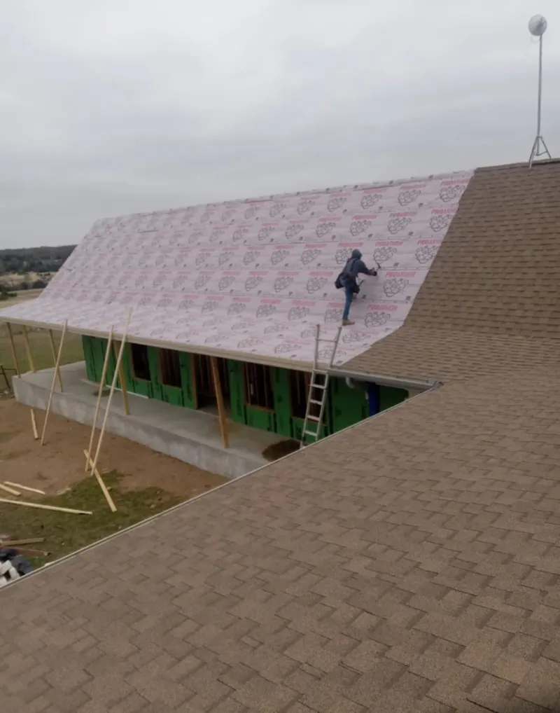 Worker preparing underlayment for a metal roof installation in Pataskala